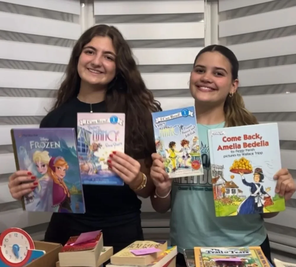 Two volunteers holding children's books collected during a book drive