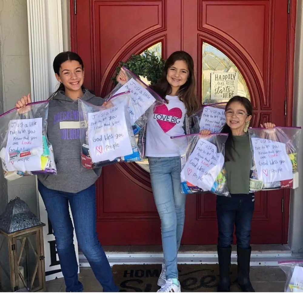 Three young volunteers holding care packages with handwritten notes